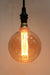 Round amber bulb with laser-cut filament on pendant cord