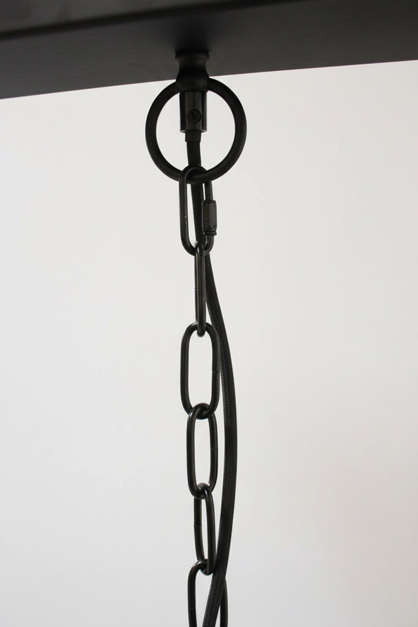 Black chain suspension hanging against a black ceiling rose