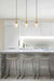 three glass pendant lights in the gold/brass finish hung from ceiling within a kitchen interior. 