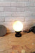 Glass ball lamp with black base on table