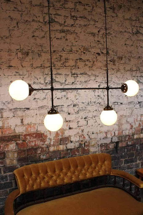 The Glass Ball Junction Pendant Light is a classic deco industrial light on heavy brass frame with opal glass shades ideal for dining room lighting or cafe lighting