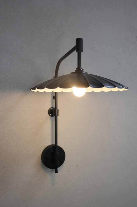 Umbrella wing arm wall lamp with large black shade on a moveable wall