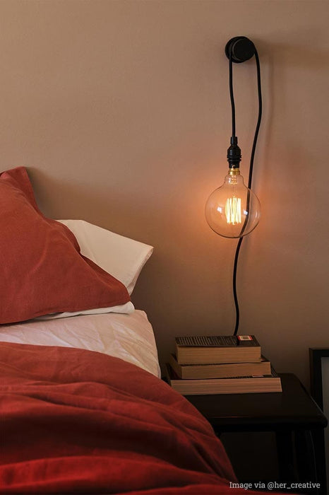 Pendant light cord with edison bulb over bedside table.