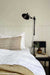 bakelight swing arm wall lamp with wall plug on one side of the bed.