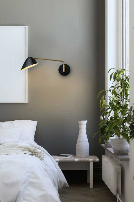 Adjustable steel wall light over a bedside table.