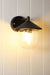 Black variant of Cabin Outdoor Wall Light affixed on white wooden panel wall