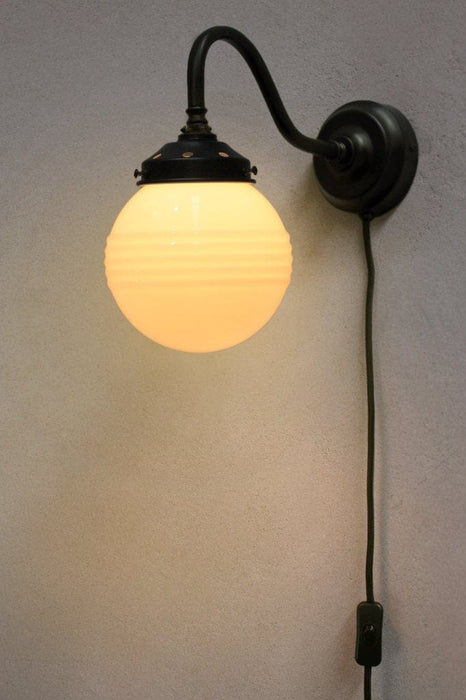 Black gooseneck wall light with small ridged opal glass shade with wall plug