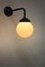 Steel wall light in a black finish with small ridged opal glass ball shade