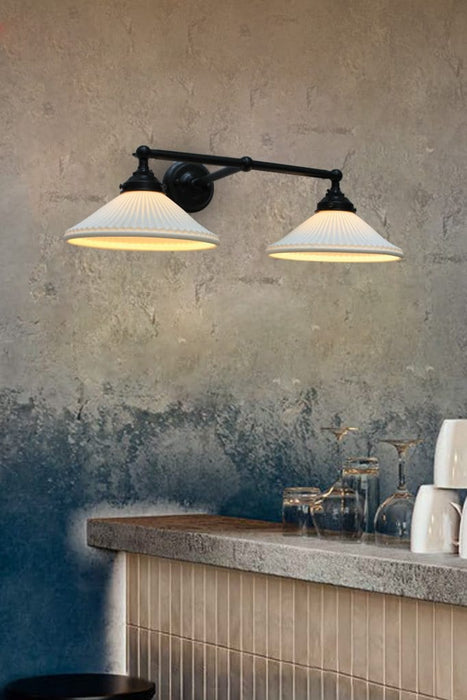 Double arm wall light with pleated ceramic shades mounted above a bar