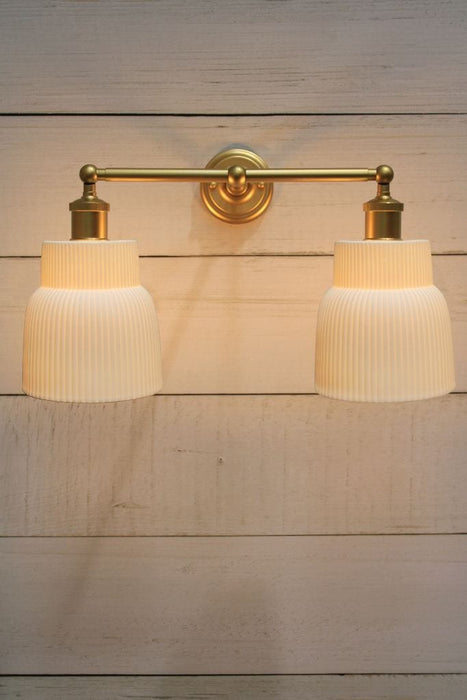 Double swivel arm wall light in gold/brass finish with two ceramic shades