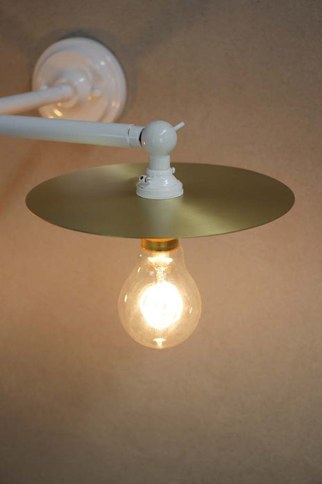 White wall light with small brass disc