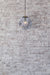 Small smoked glass pendant against white washed brick wall. 