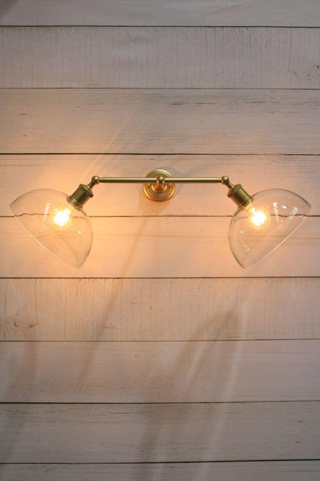 Gold steel double arm wall sconce with clear dome shades