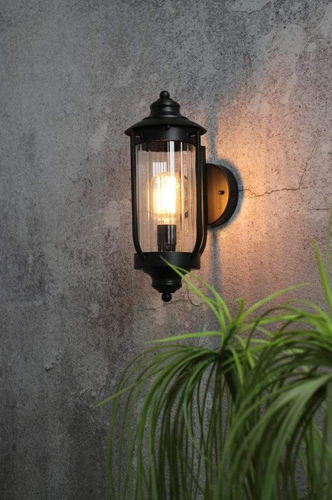 Black outdoor wall light with clear glass shade.