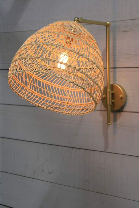 gold/brass wall light with woven rattan shade tilted on angle