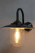 Boathouse glass wall light has a protective glass shade to house its edison filament led light bulb and sits on a black gooseneck wall sconce.