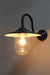 Boathouse glass wall light has a protective glass shade to house its edsion light bulb and sits on a black gooseneck wall sconce. glossy black shade with white inner holds the bulb