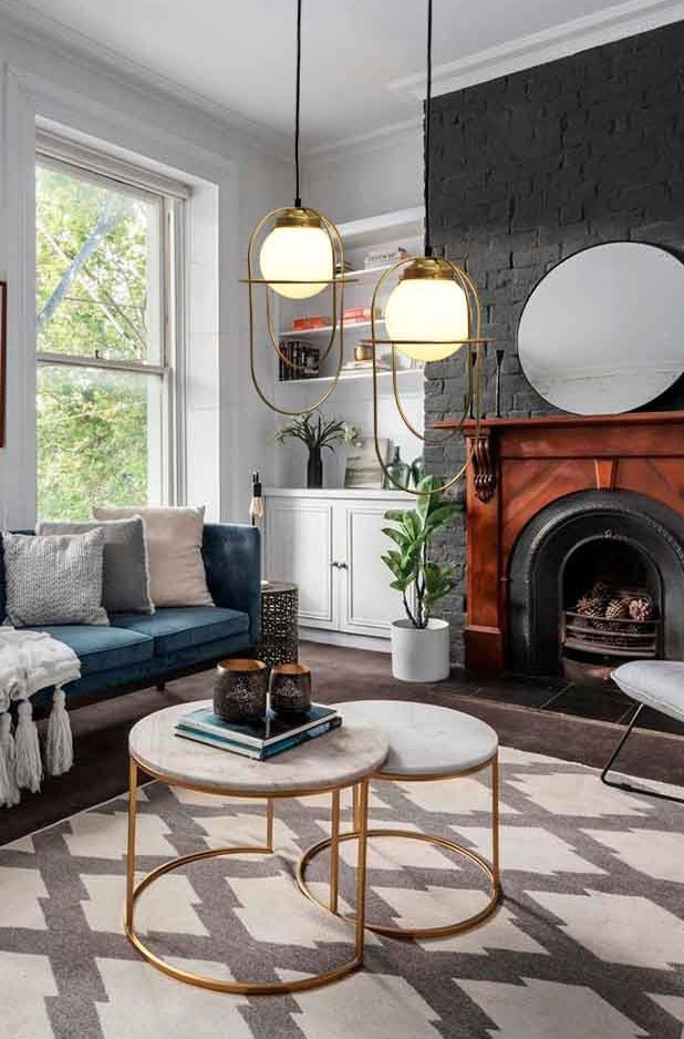 2 Pendant lights with opal glass ball shade and gold/brass metalware hanging over coffee table in a living room.
