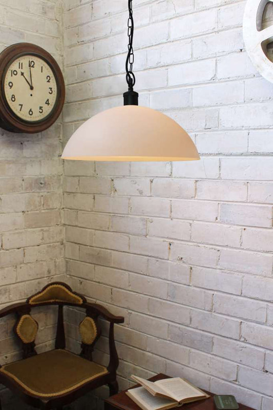 Large opal glass pendant with black chain against a white brick wall