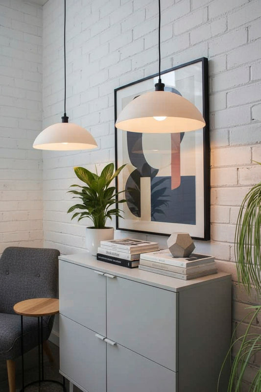 Two opal glass pendant lights suspended next to a white brick wall