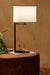 White shade black base lamp in a earthy toned lounge setting 