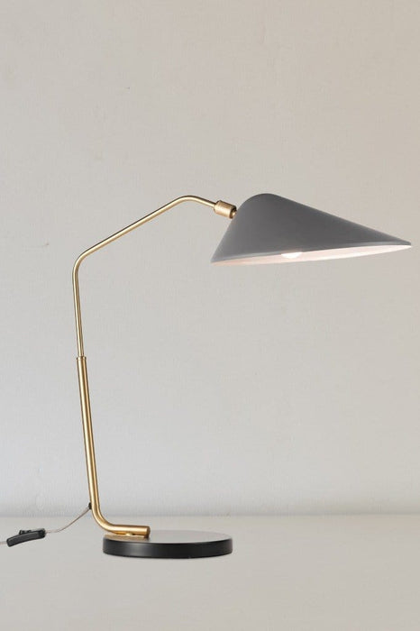 Mid-century style table lamp with gold brass fixtures, a round black base and satin grey shade