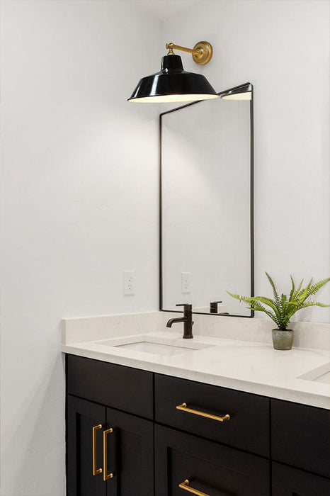 Black wall light over over a mirror in a bathroom.