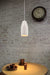 White metal pendant above a timber laminate table with a white brick background